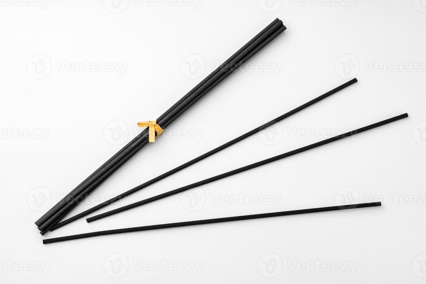 Black aromatic sticks resting on a plain white background photo