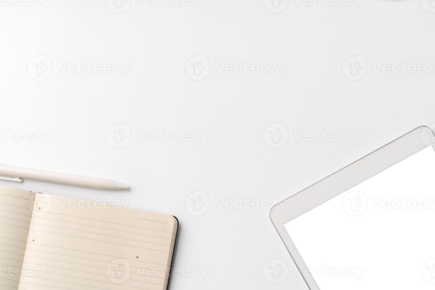 Digital tablet on white desk with notepad and pen photo