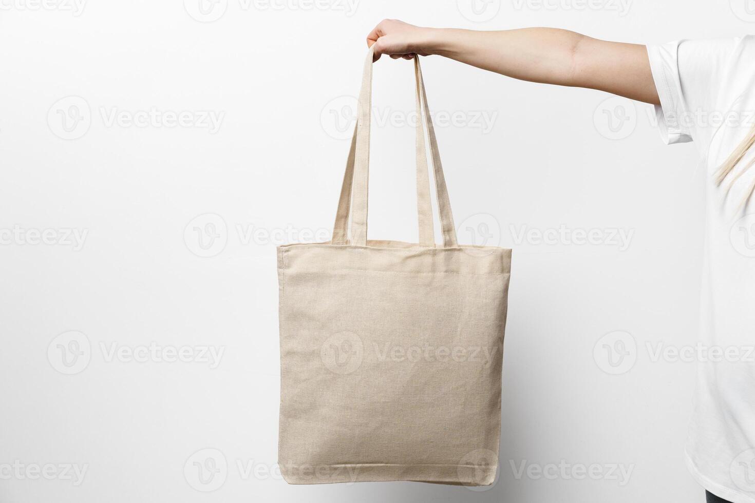 Female hand holding eco or reusable shopping bag against white background photo