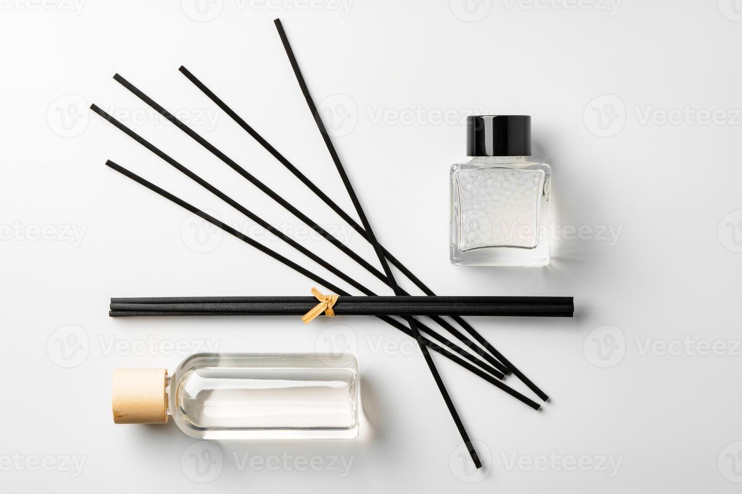 A minimalist display of essential oil and black diffuser sticks on a clean white background photo