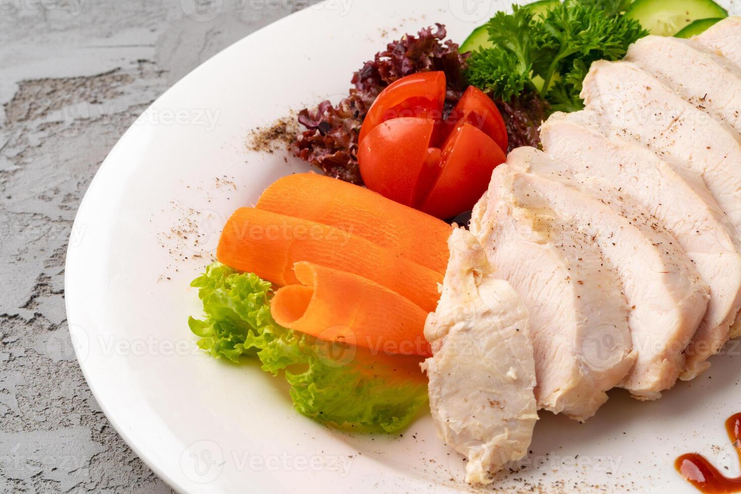 Roast chicken fillets and vegetables on gray background photo