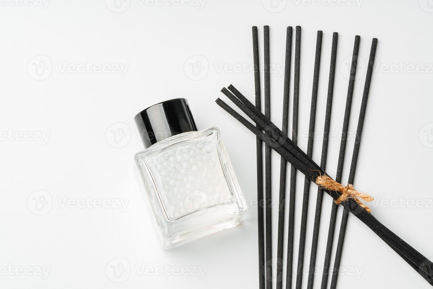 A minimalist display of essential oil and black diffuser sticks on a clean white background photo
