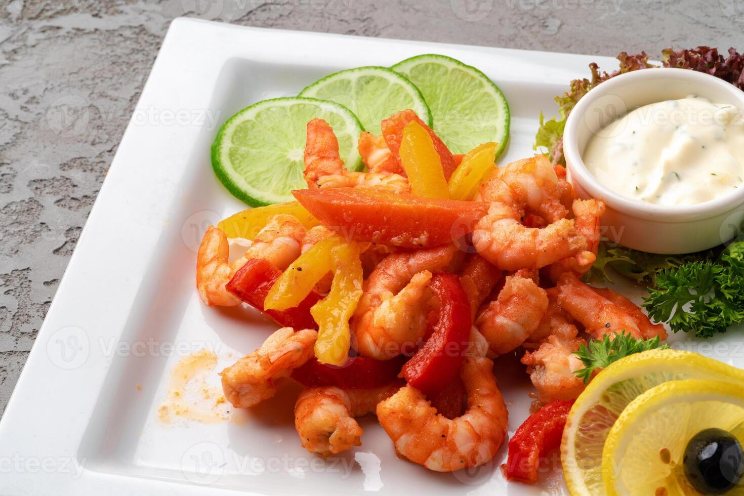 Shrimps fried with vegetables on white plate with sauce photo