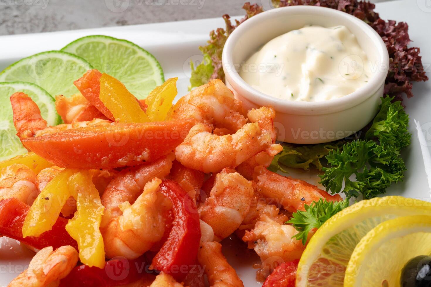 Shrimps fried with vegetables on white plate with sauce photo