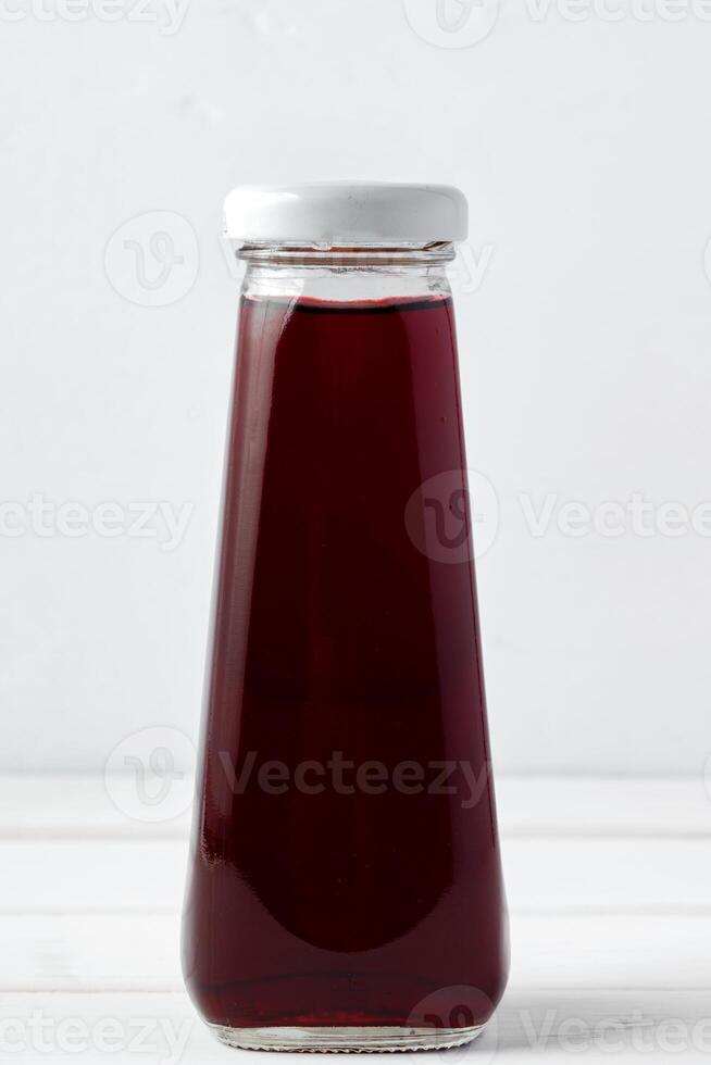 Small glass bottle of fresh juice on white background photo