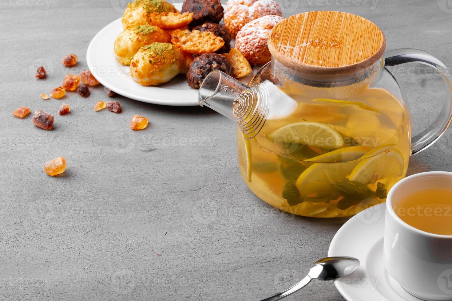 Glass teapot with fruit tea and cookies on gray background photo