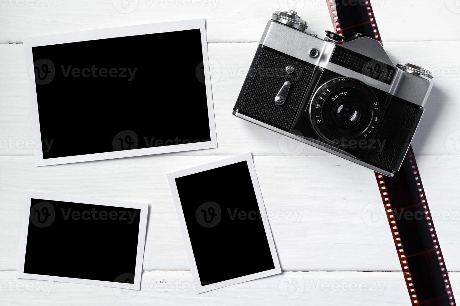 Old retro camera and photos on white wooden background
