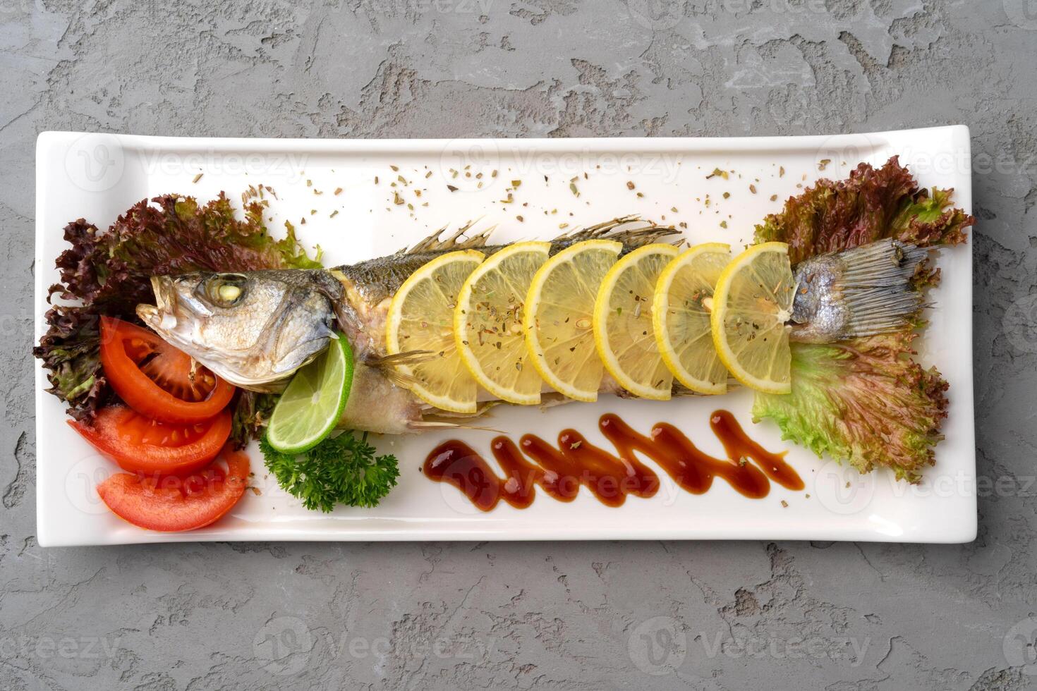 Fresh sea fish with lemon on plate photo