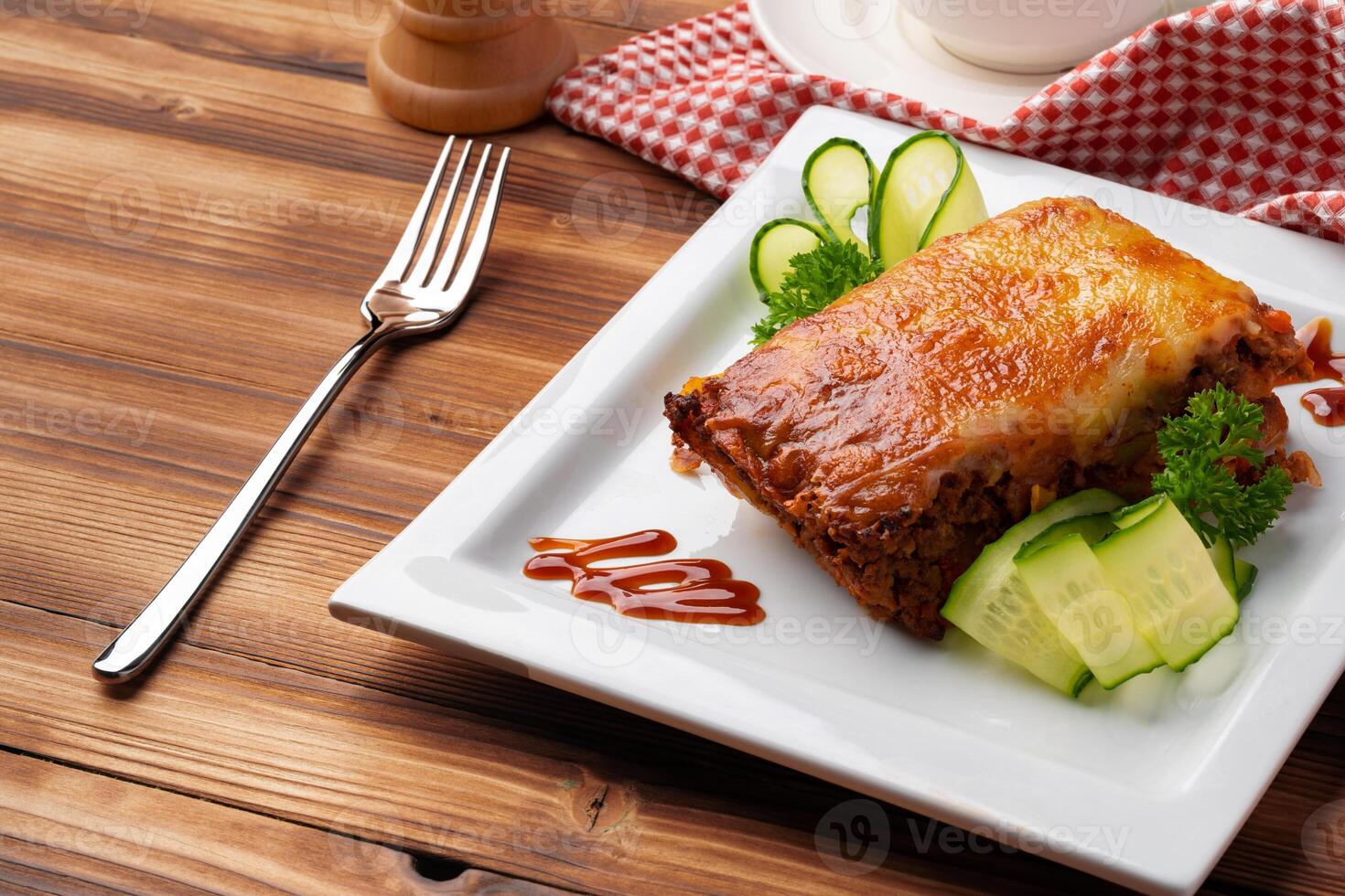 Tasty lasagne served on plate on wooden background photo