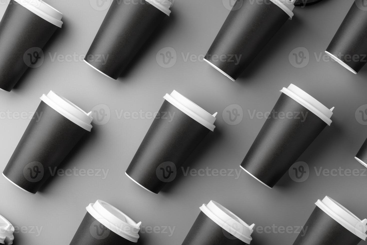 Black disposable cups arranged on a gray surface with white lids, creating a look suitable for a coffee shop setting photo