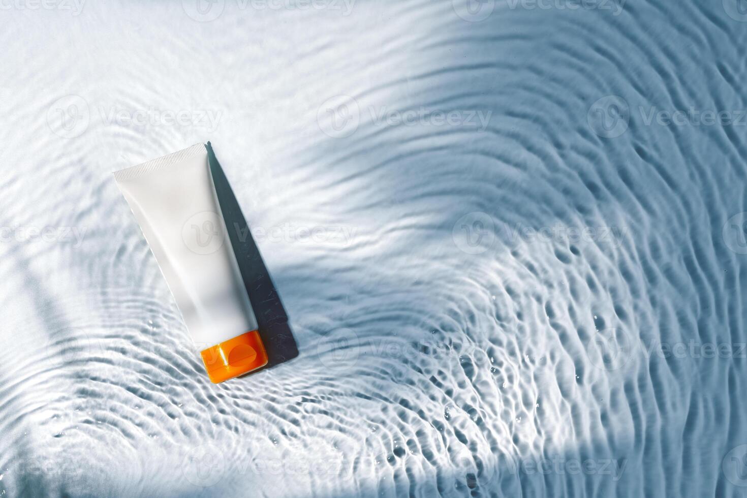 Tropical setting with a skincare tube resting on textured white surface illuminated by sunlight photo
