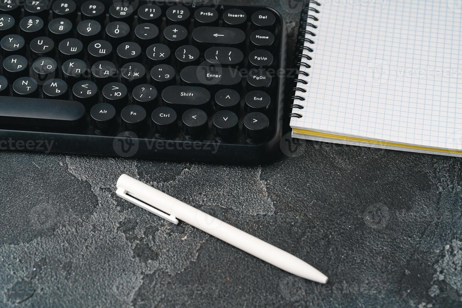 Office desk with computer keyboard, notepad and pen photo