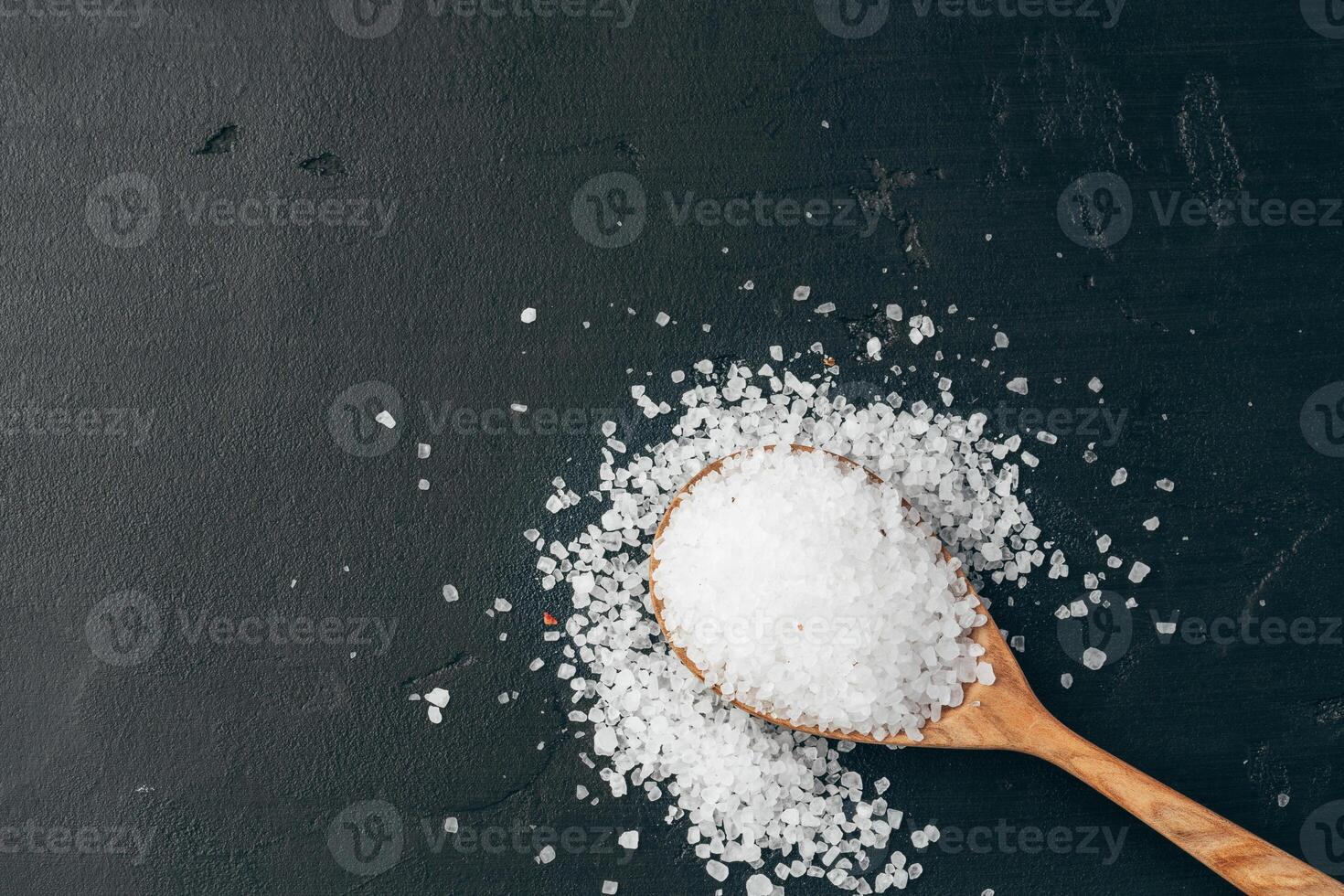 Sea salt on wooden spoon on black background photo