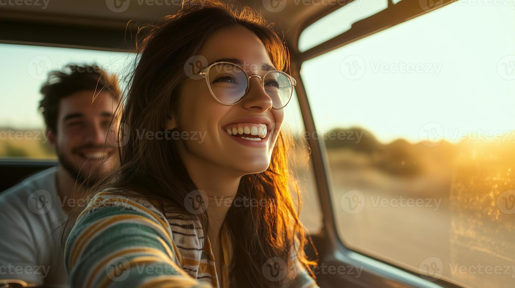 A joyful couple enjoys a sunset drive through scenic countryside with warm sunlight illuminating their faces photo