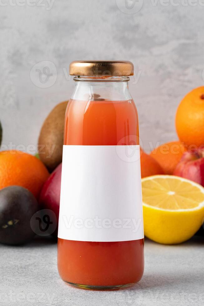 Various fruits and freshly squeezed fruits juice in bottle on gray background photo