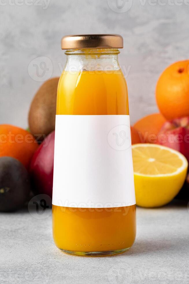 Various fruits and freshly squeezed fruits juice in bottle on gray background photo
