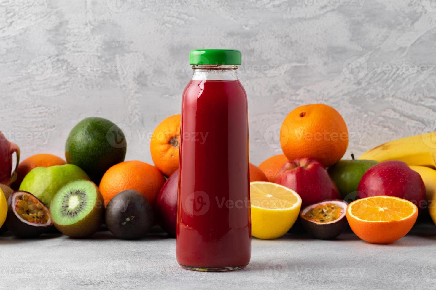Various fruits and freshly squeezed fruits juice in bottle on gray background photo