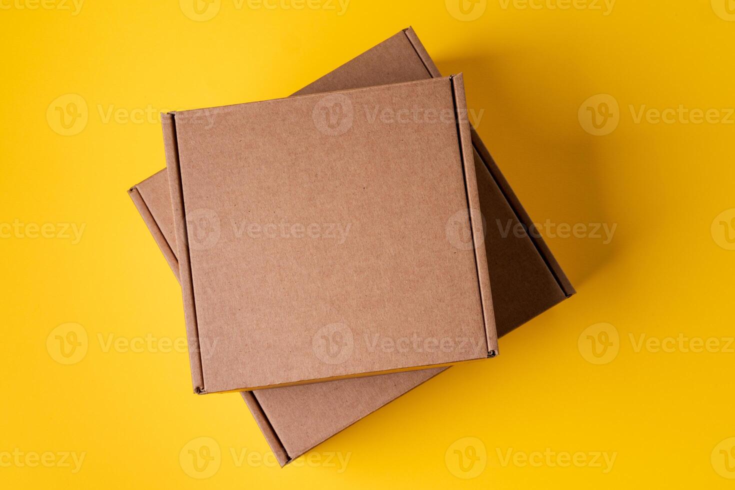 Beige cardboard boxes on yellow background, close up photo