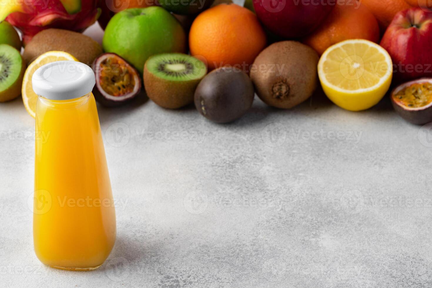 Various fruits and freshly squeezed fruits juice in bottle on gray background photo