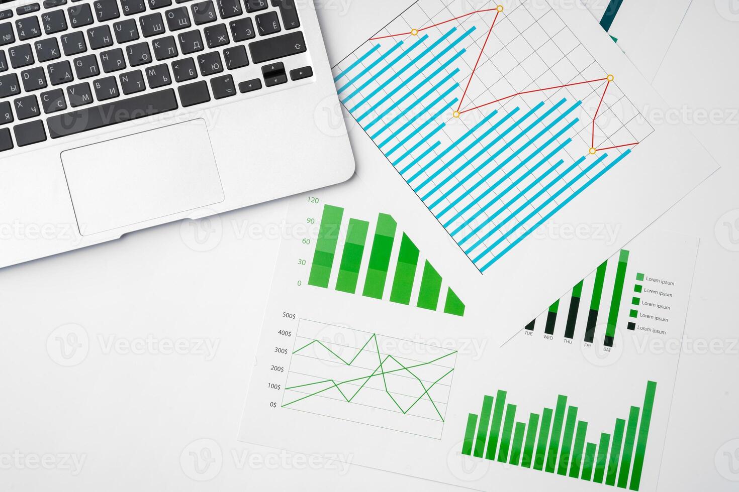 Paper statistics charts and laptop keyboard on white table photo