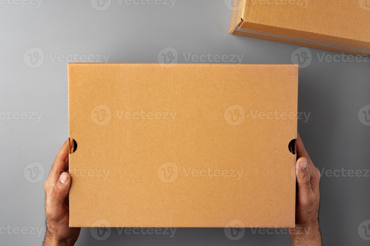 Parcel cardboard box in a man hands on a gray table background photo