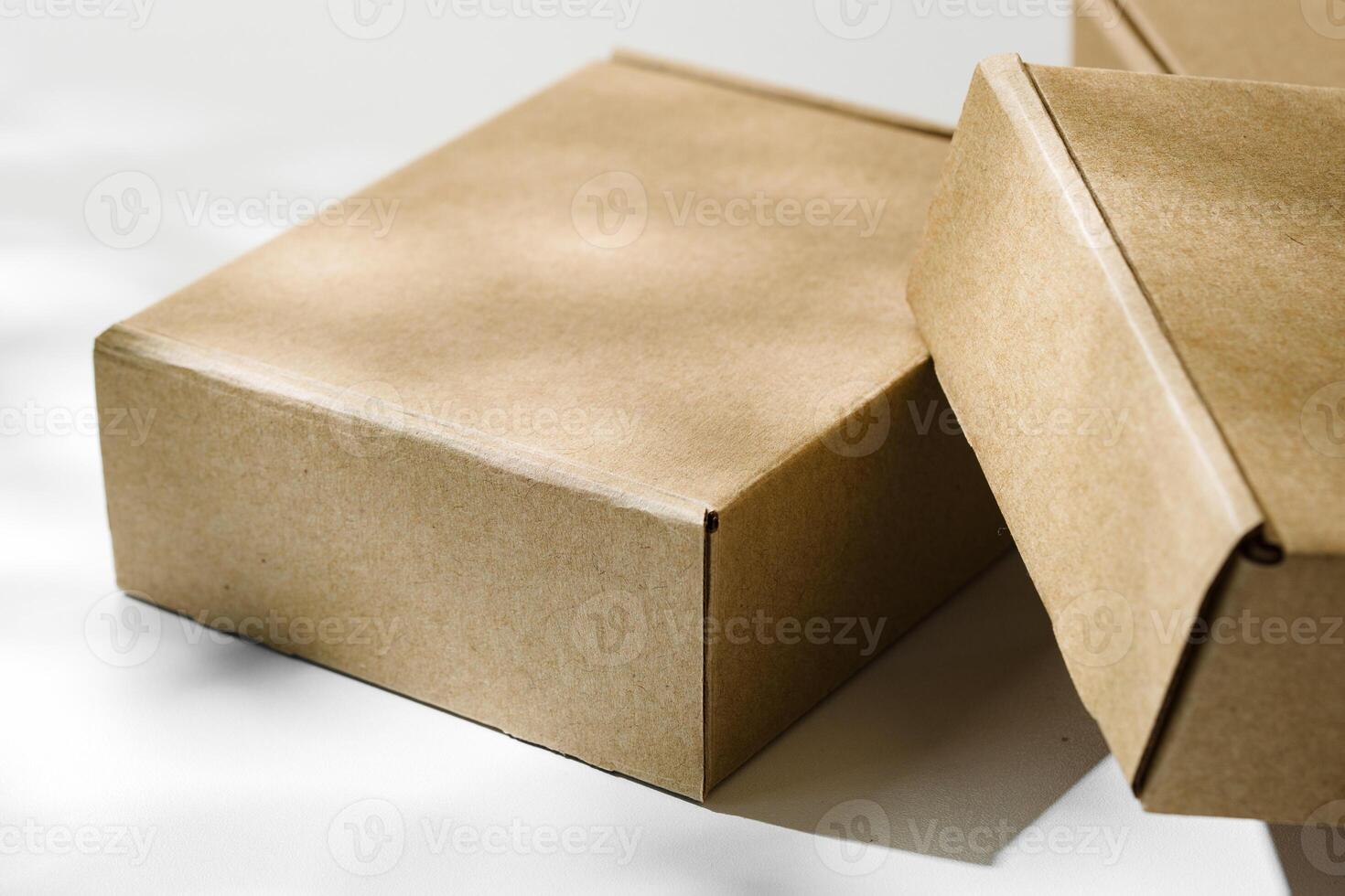 Three brown cardboard boxes arranged on a light surface with soft shadows photo