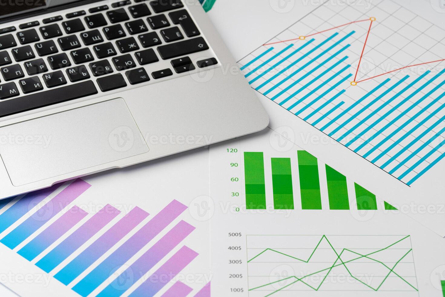 Paper statistics charts and laptop keyboard on white table photo