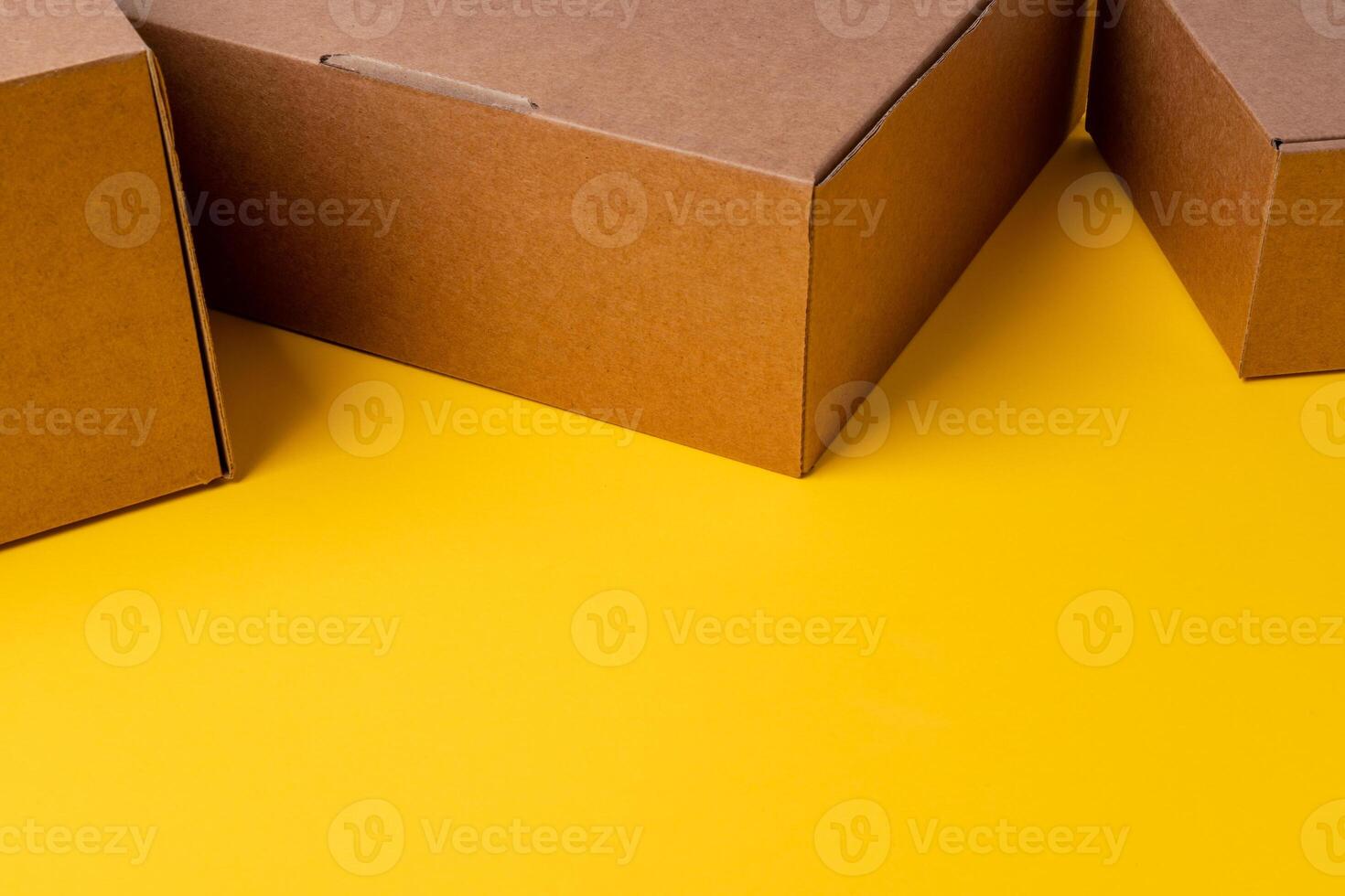 Beige cardboard boxes on yellow background, close up photo