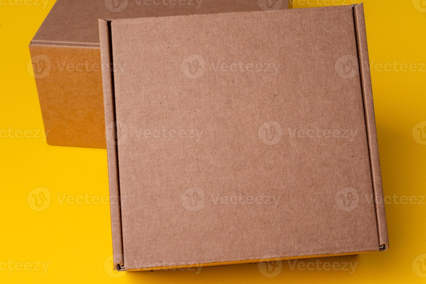 Beige cardboard boxes on yellow background, close up photo