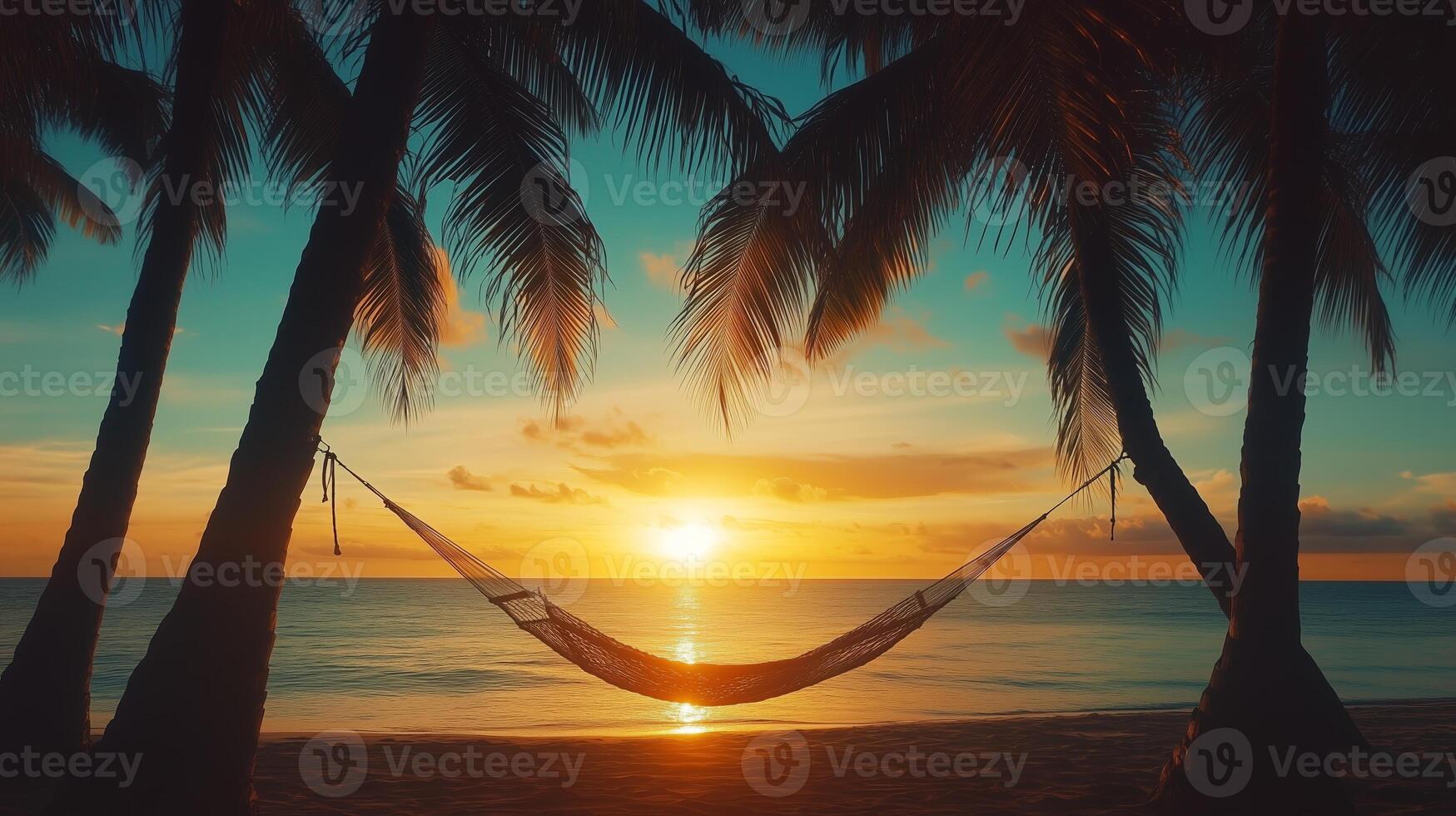 Serene sunset view over the ocean with a hammock strung between palm trees on a sandy beach photo