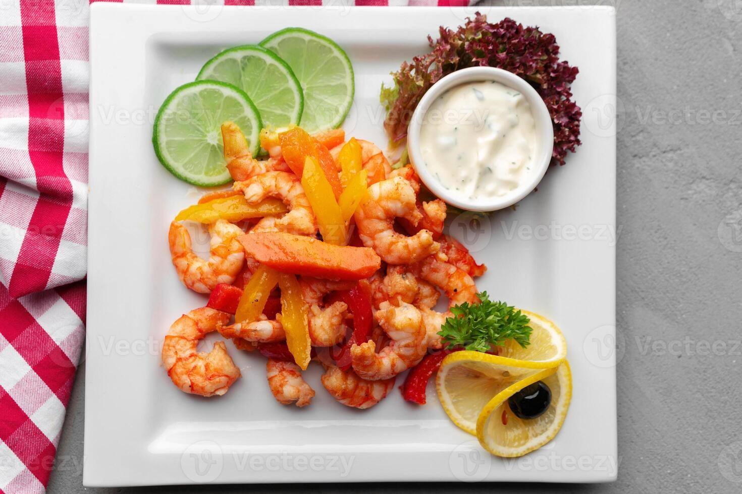 Spicy garlic chilli shrimps in white plate on gray background photo