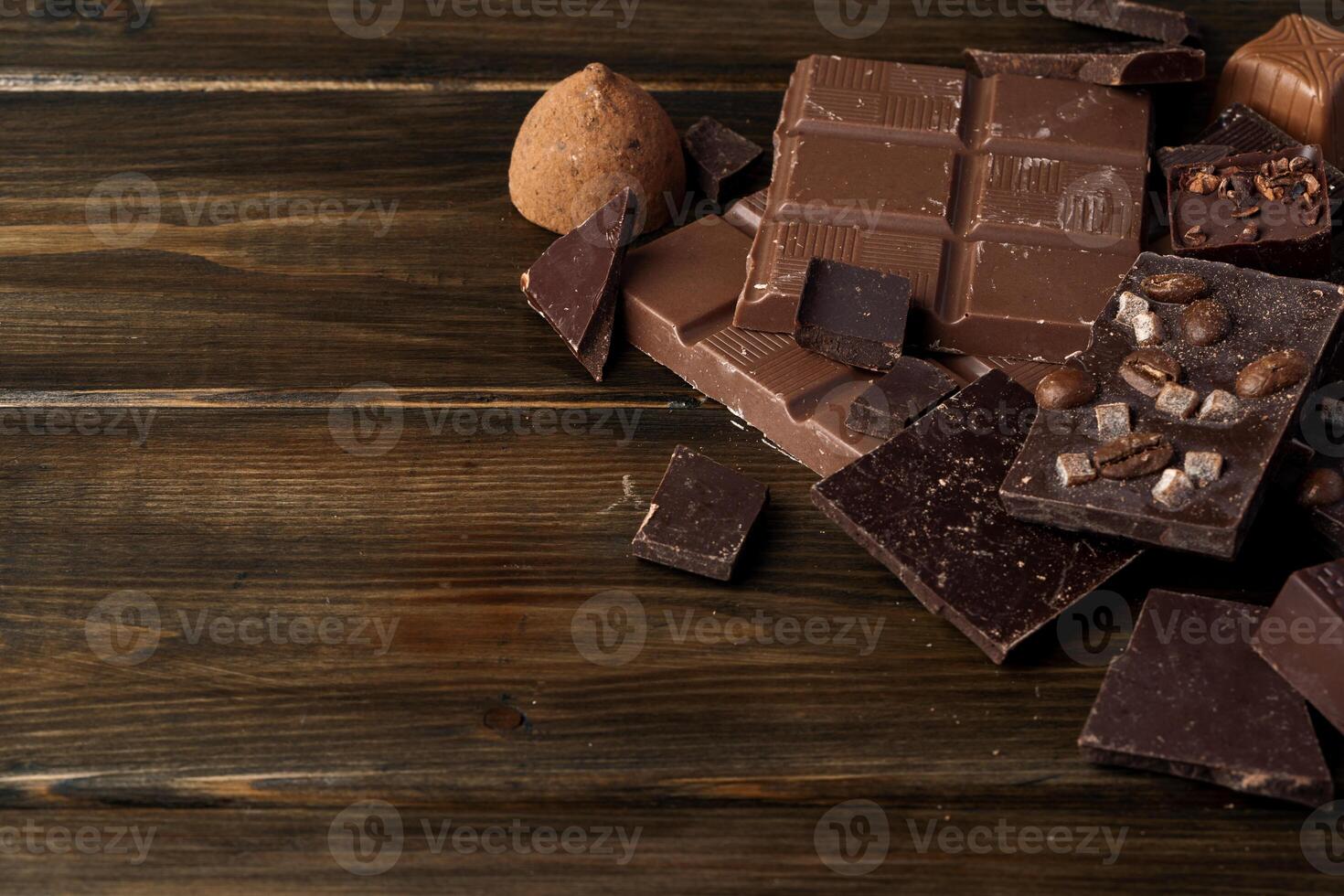 Broken chocolate bars on dark wooden background photo