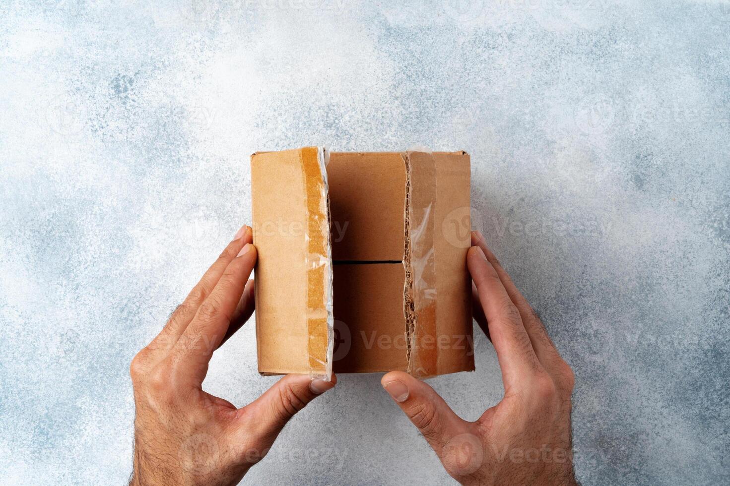 Parcel cardboard box in a man hands on a gray table background photo