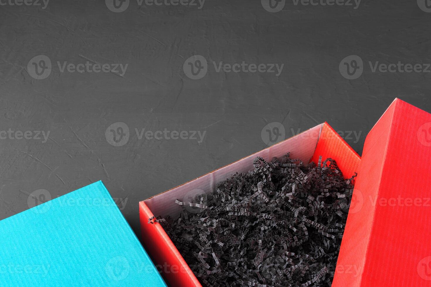Open red paper box with tinsel on black background photo