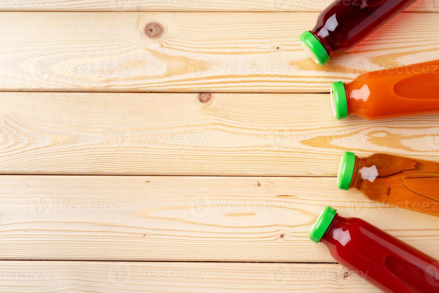 Different bottles of juice on wooden table photo
