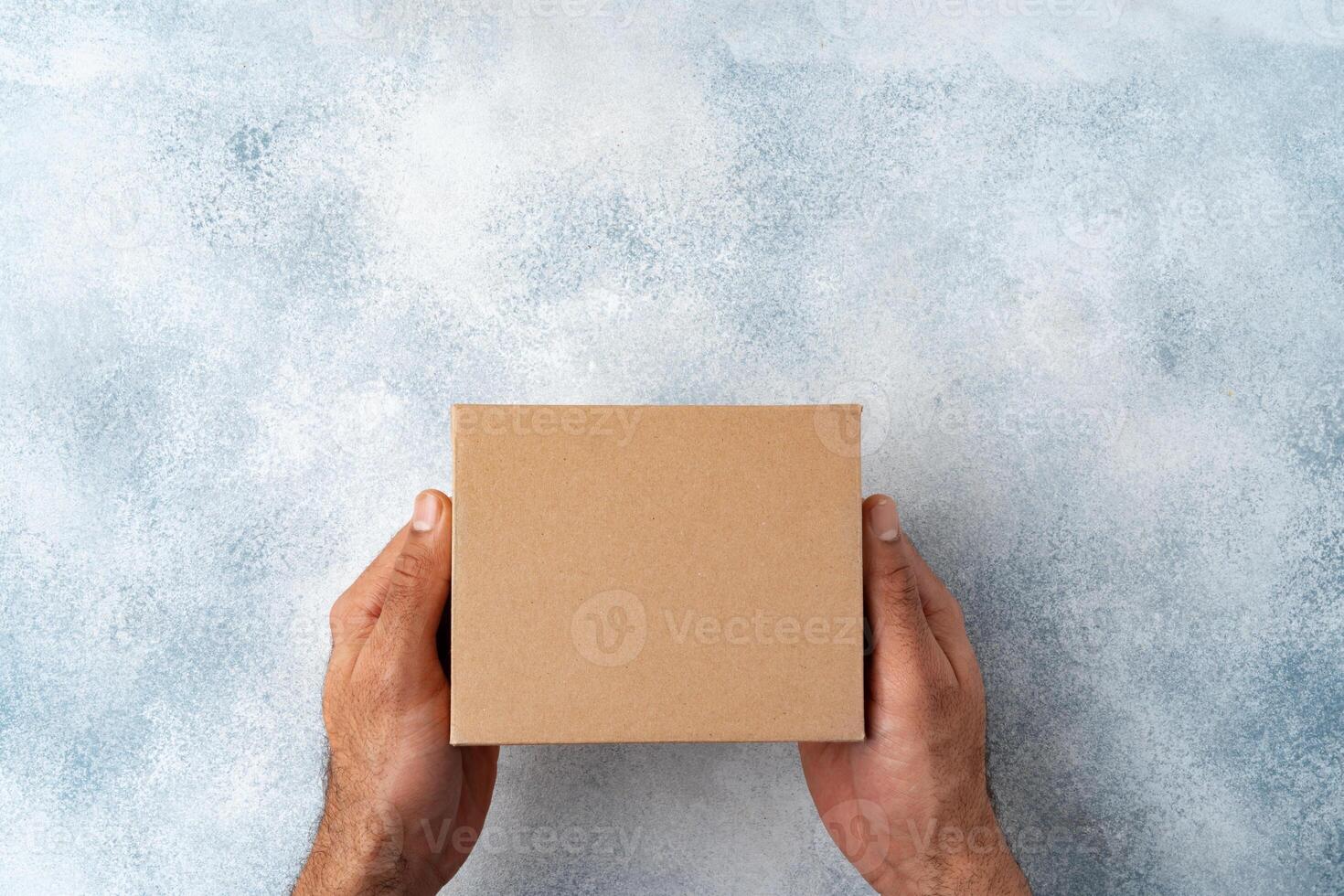 Parcel cardboard box in a man hands on a gray table background photo