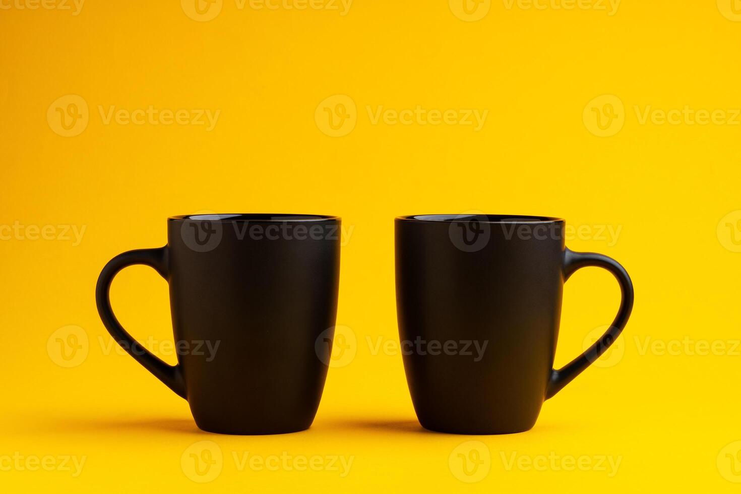 Two mugs on yellow studio background close up photo
