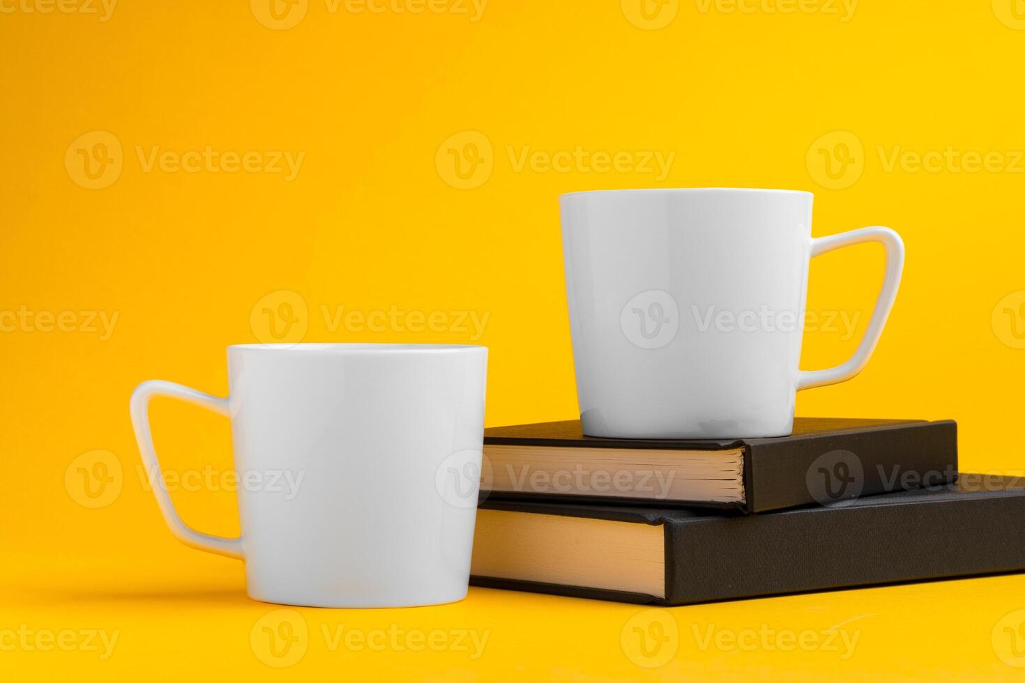 Two mugs on yellow studio background close up photo