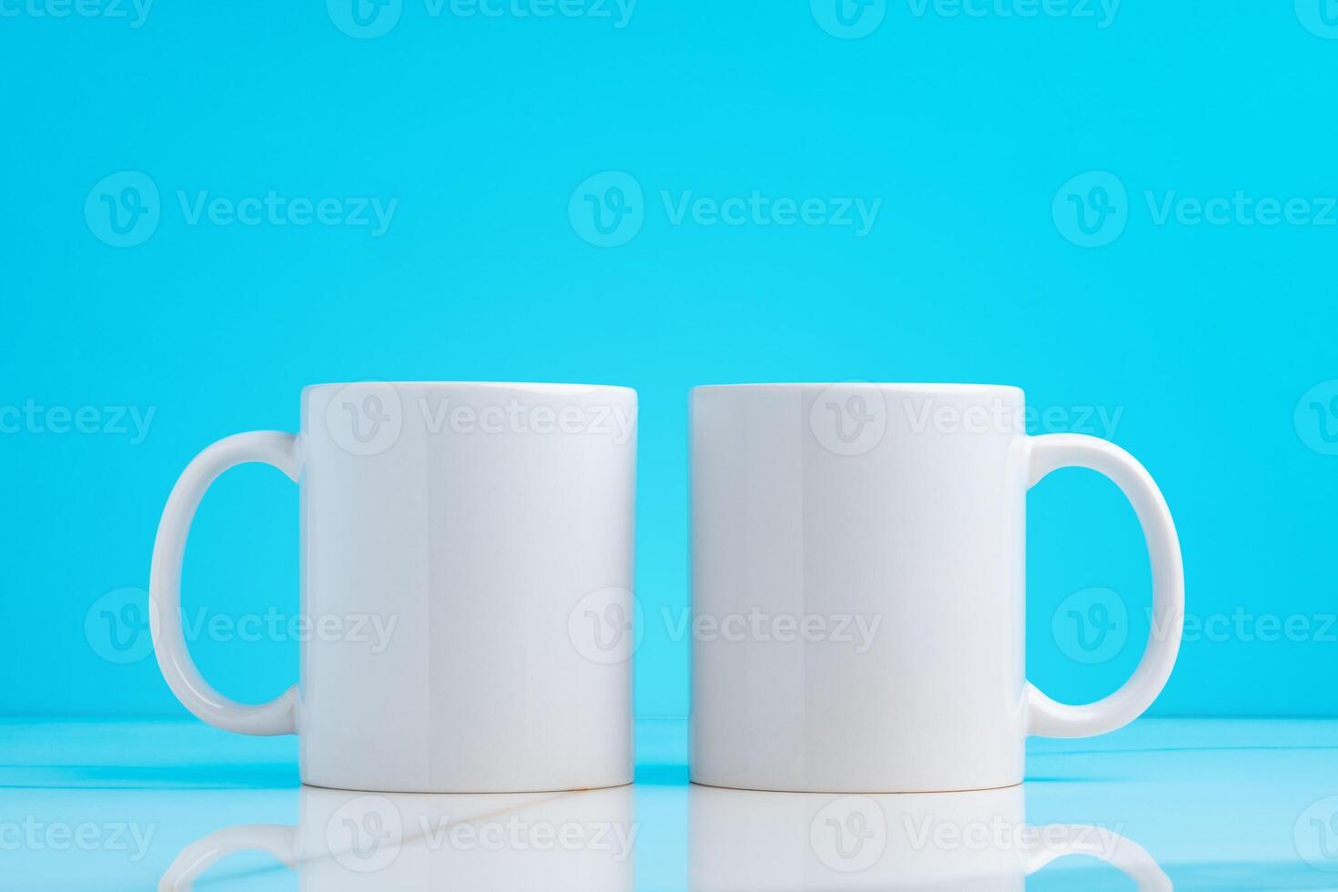 Two ceramic mugs on blue studio background photo