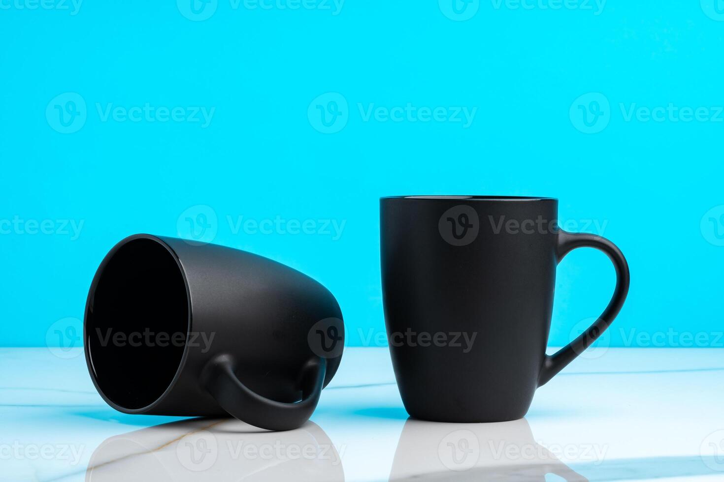 Two ceramic mugs on blue studio background photo
