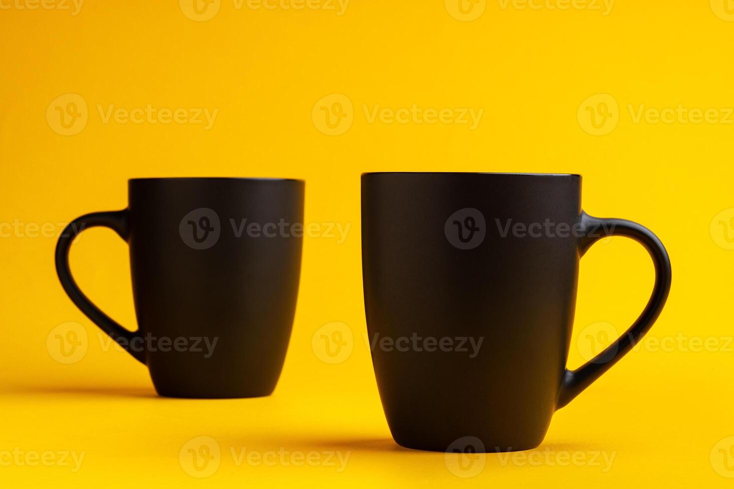 Two mugs on yellow studio background close up photo