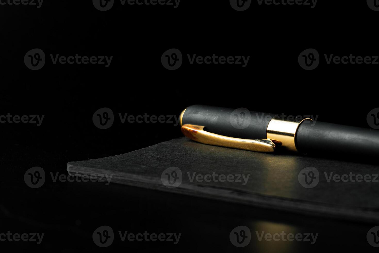 Black notepad with pen on black table close up photo