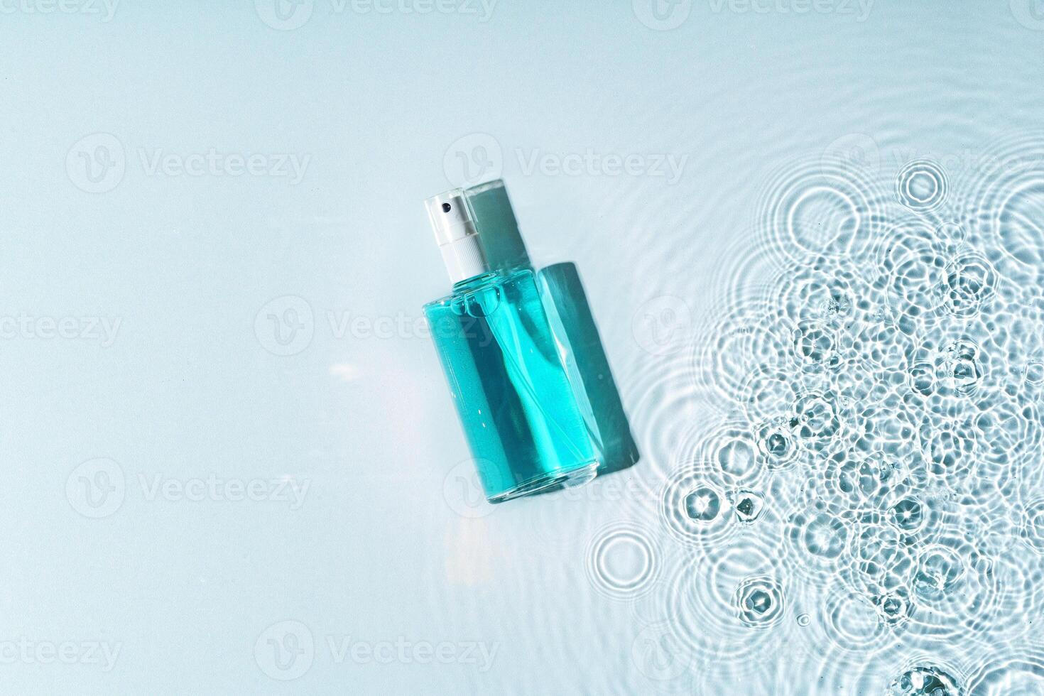 Clear bottle of gel product resting on a light blue surface with water droplets photo