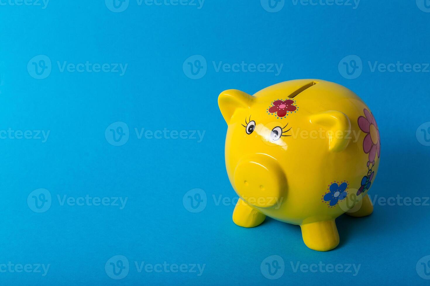 Yellow piggy bank on blue background photo