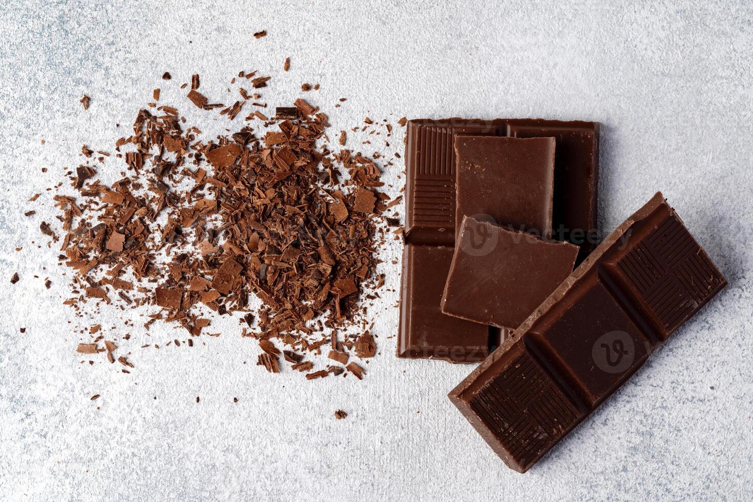 Grated chocolate and pieces of tasty chocolate on table photo