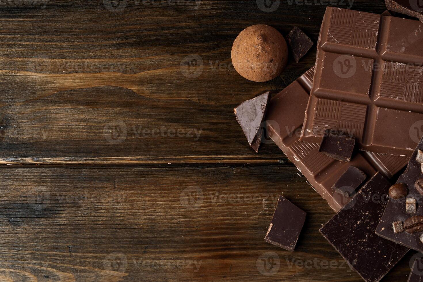 Broken chocolate bars on dark wooden background photo