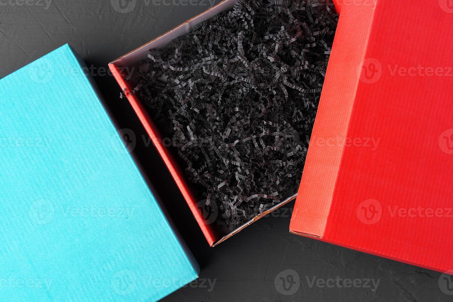 Open red paper box with tinsel on black background photo