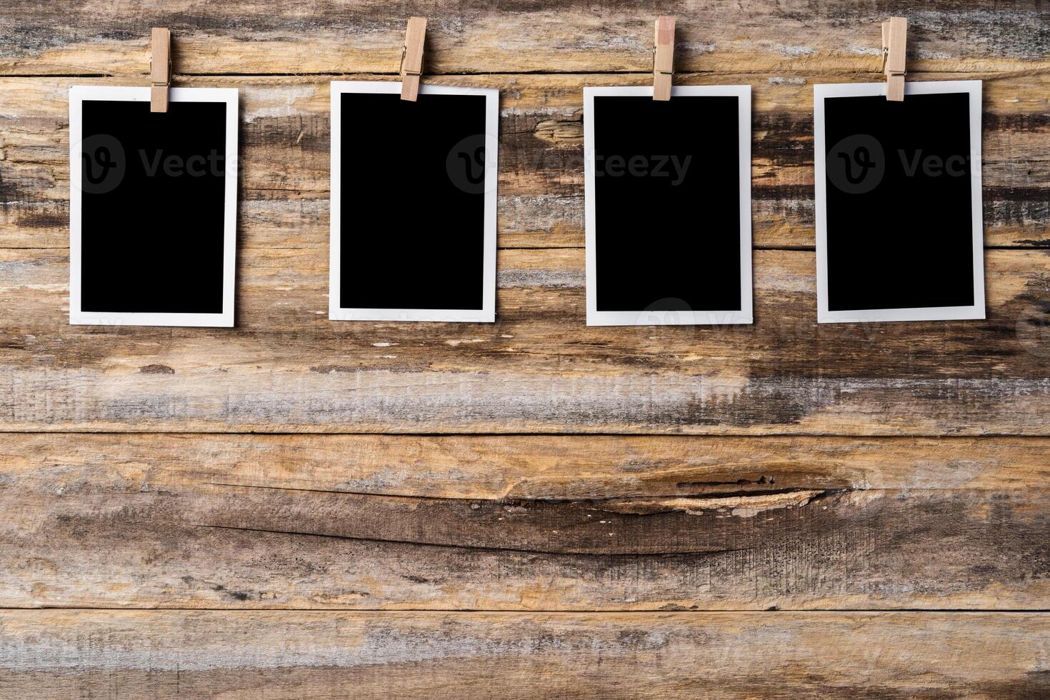Paper blank photo frames hanging on wooden wall