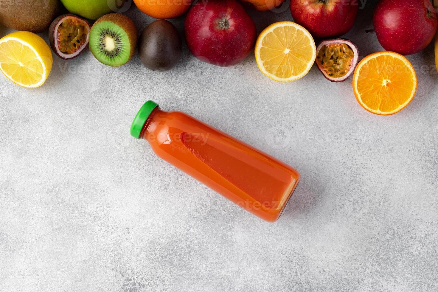Various fruits and freshly squeezed fruits juice in bottle on gray background photo