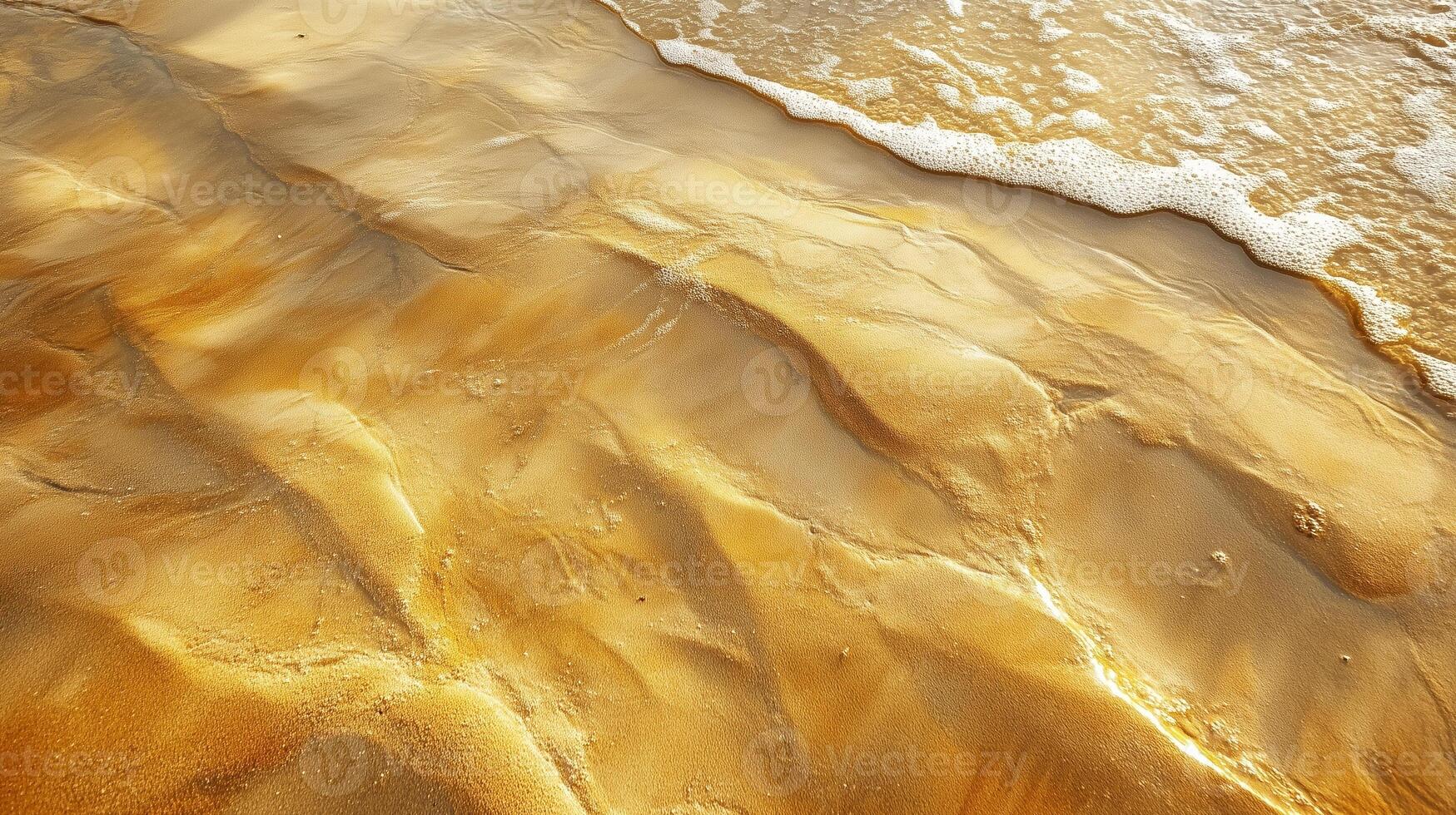 Golden sand patterns at the beach during sunset with gentle waves lapping at the shore photo